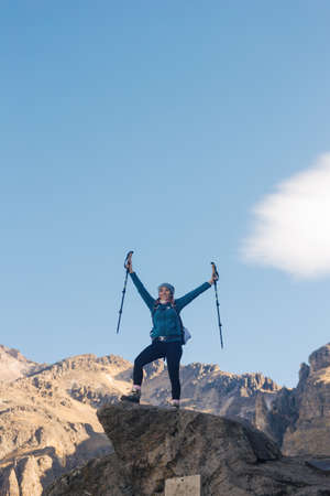 mujer con bastones de trekking de pie en la cima de la montaña