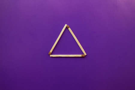 Isosceles triangle on a bright background matchstick pyramid on cardboard education concept