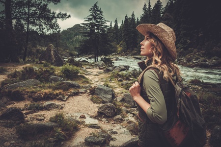 Beautiful woman hiker walking near wild mountain river