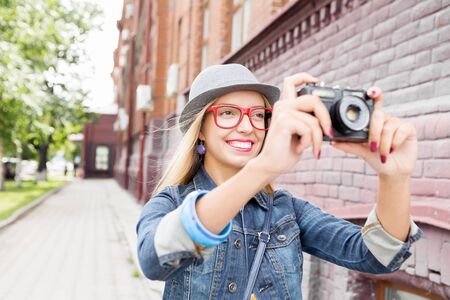 Młoda podróżniczka chodząca po ulicy i robiąca zdjęcia starym aparatem