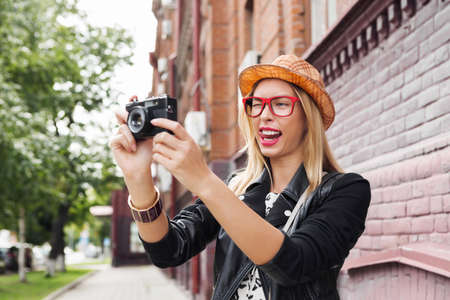 Młoda podróżniczka chodząca po ulicy i robiąca zdjęcia starym aparatem