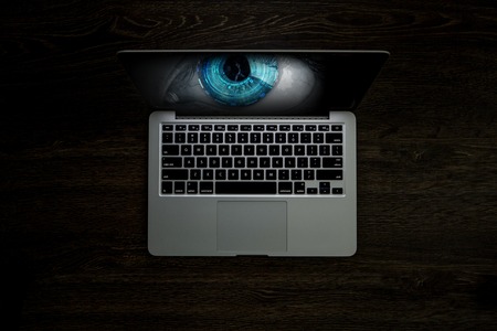 Opened laptop and human eye on screen against dark background