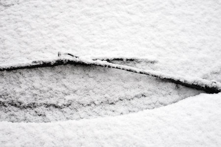 Closeup of windscreen of car parked in the street covered by the snow