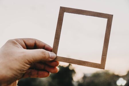 Hand holding blank paper frame with nature bokeh background text concept