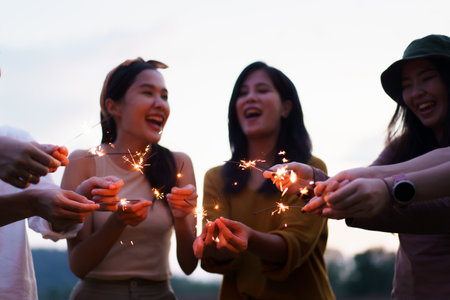 Group of asian young men and women celebrating together with a sparkling firework in the evening happy men and women enjoy playing a sparklers firework in a party