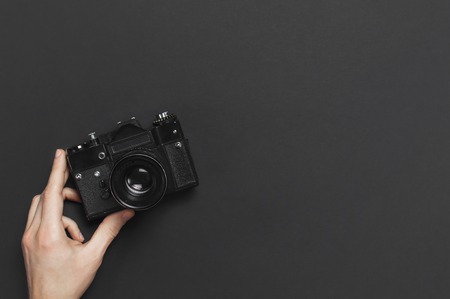 Mannelijke handen houden oude vintage camera op zwarte achtergrond bovenzicht vlak lag met kopieerruimte. Concept voor de fotograaf, oude fotografische apparatuur minimalistische stijl