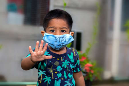 Retrato de un niño pequeño que lleva una máscara médica y viaja por el jardín. Proteger de la infección por coronavirus en cuarentena domiciliaria.