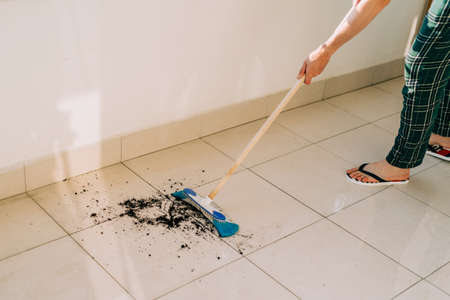 Hombre limpiando el suelo con la fregona. Conserje lavando los pisos sucios. Chico trapeando el balcón en un día soleado. Persona que realiza las tareas del hogar. Compañero joven que usa equipo de limpieza para desempolvar la superficie.