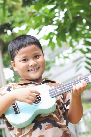 Boy playing the ukulele fun Фото со стока