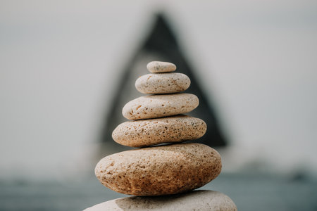 Balanced rock pyramid on sea pebbles beach sunny day and clear sky at sunset golden sea bokeh on background selective focus zen stones on sea beach meditation spa harmony calm balance concept Stock Photo