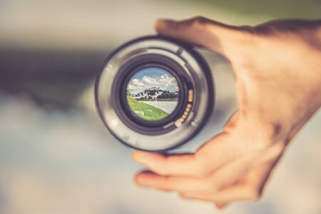 Hand holding camera lens with old city of salzburg in it close up