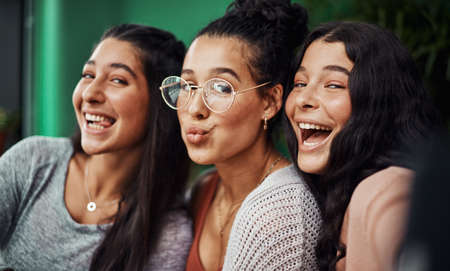 La vida es buena cuando tienes a tus chicas. Foto de hermanas jóvenes tomándose selfies juntas en un café.