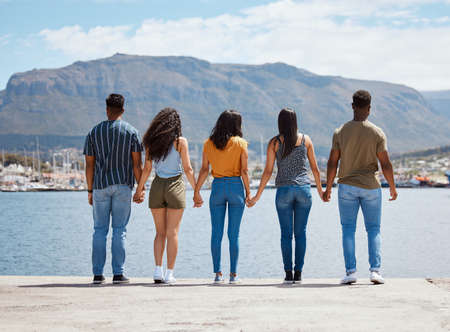 Los verdaderos amigos nunca se separan. foto retrovisora de un grupo de amigos tomados de la mano mientras están de pie juntos en un muelle.