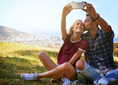 Taking a selfie in the sunlight an affectionate young couple enjoying a day outdoors