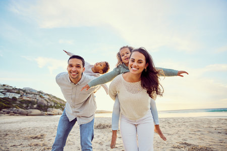 Familia de raza mixta sin preocupaciones caminando y divirtiéndose juntos en la playa. padres pasando tiempo con su hijo e hija durante las vacaciones. hermanitos jugando con sus padres de vacaciones