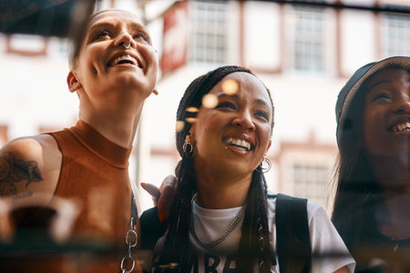 Ventana de un café y un grupo de mujeres sonrientes uniéndose y almorzando juntas en la acera de la ciudad, divertidas y amigas felices revisando la elección del menú en un restaurante para un brunch urbano el fin de semana de verano Foto de archivo