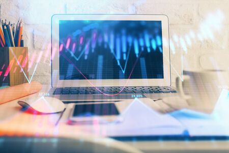 Stock market graph on background with desk and personal computer double exposure concept of financial analysis