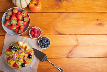 Homemade fruit pie with strawberries raspberries blueberries kiwi melon and apple on a rustic table