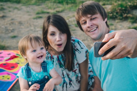 szczęśliwa młoda rodzina biorąc selfie podczas gry z latawcem Zdjęcie Seryjne