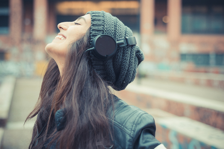 Young beautiful brunette woman listening music with headphones in the city