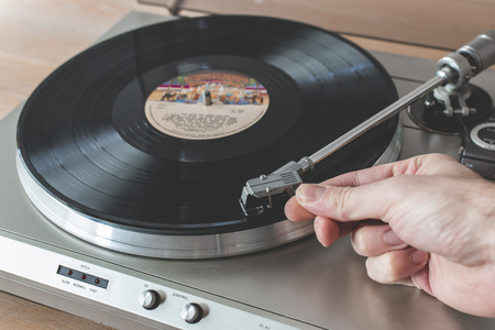 Mano colocando la aguja de un tocadiscos en un disco de vinilo giratorio