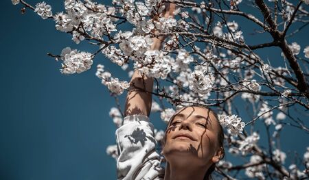 Glückliches Mädchen, das das Aroma eines sanft blühenden Kirschbaums genießt