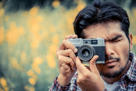 Jonge hipster man die foto neemt met oude stijl camera met natuurlandschap achtergrond. Retro en vintage fotografie concept.