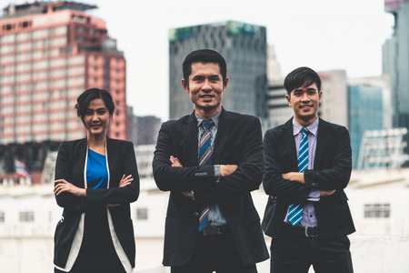 Three business people standing with arms crossed and confident