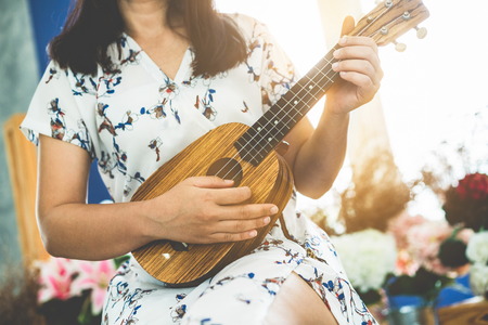 Happy woman musician playing ukulele and singing a song in sound studio music lifestyle concept