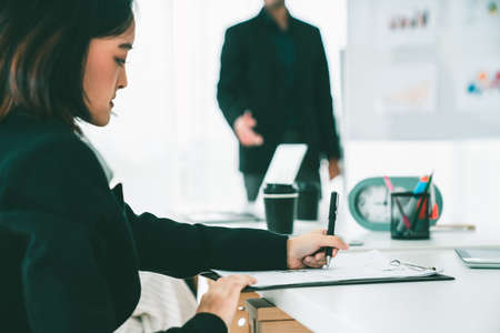 Empresaria en una reunión de negocios escribiendo papel de manera competente en la sala de la oficina. Colaboración del equipo de negocios corporativos