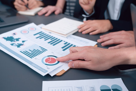 Closeup on bi dashboard on meeting desk with businesspeople analyzing or planning business strategy with hands pointing on financial paper reports as concept of harmony in office workplace