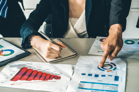 Businessman and businesswoman in meeting working with many financial statement document on desk concept of busy business profit analysis and brainstorm close up shot at people hands and papers uds