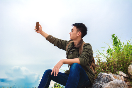 Young man using smartphone man holding mobile smartphone using app texting sms message wearing jacket jean wearing black sunglasses on mountain nature background