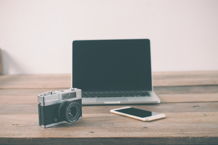 Wooden table work place of hipster person laptop retro camera smartphone on table