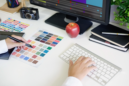 Closeup graphic designer using digital tablet and computer in the office