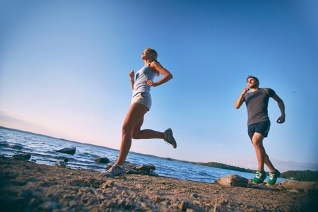 Photo of young couple running on the coastline