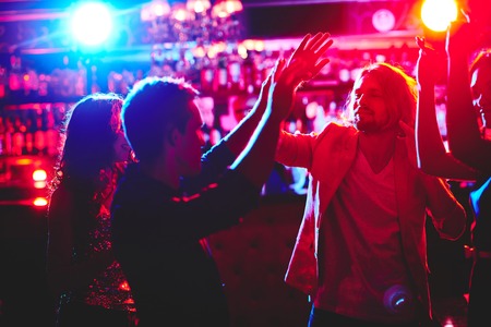 Group of happy friends dancing in nightclub