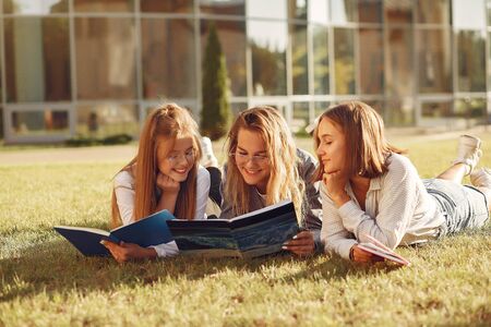 Three students lying on a grass with books