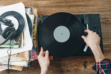 Hombre escuchando música de un disco de vinilo. reproducción de música desde un disco analógico en un tocadiscos. disfrutando de la música de la colección antigua. descansando en casa. retro y antiguo. pasión por la música