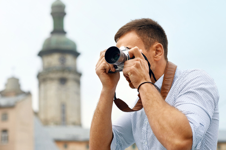 Tourist man with camera taking photos on street portrait of handsome smiling male holding camera making photo of interesting places while walking in old city travel concept high quality image