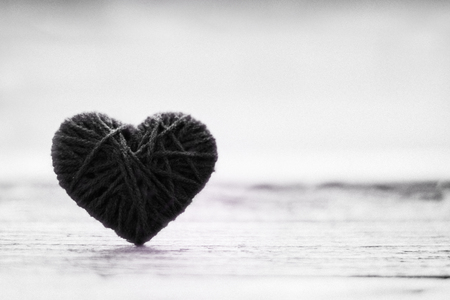 Knitting wool in shape of heart on vintage wooden with bokeh soft light background black and white Stock Photo