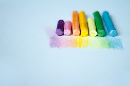 Close up view of the colorful chalk pastels on the white background soft focus