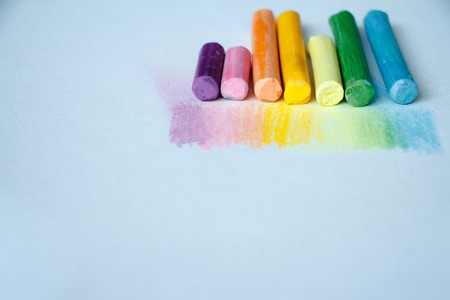 Close up view of the colorful chalk pastels on the white background soft focus