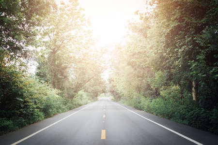 A long straight road leading towards a snow capped mountain