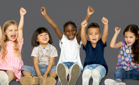 Grupo diverso de niños felices levantando las manos Foto de archivo