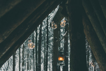 Guirnaldas y lámpara de queroseno colgando de un refugio de supervivencia en el bosque de invierno