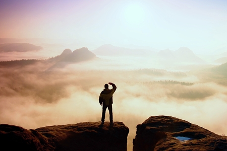 De mens staat op de top van zandsteen rots in nationaal park Saksen Zwitserland en kijken naar de zon. Prachtig moment het wonder van de natuur