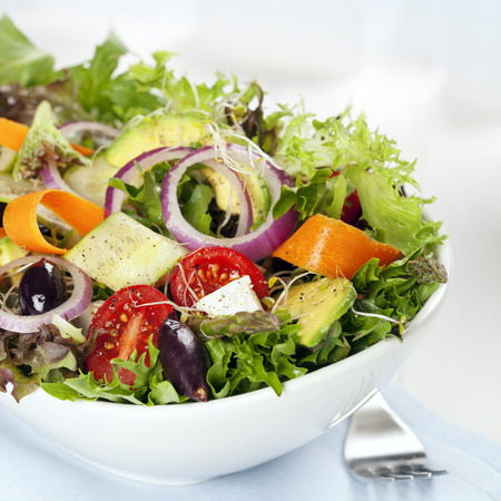 Salad in white bowl mixed greens with black olives tomatoes and lots of vegetables Stock Photo