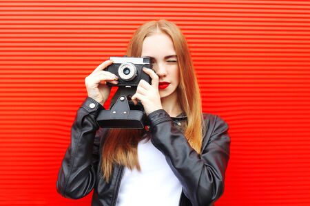 Fashion pretty woman with vintage camera in city over red background Stock Photo