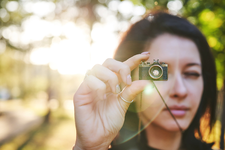 Woman photographer taking pictures on her jewelry camera at sunset